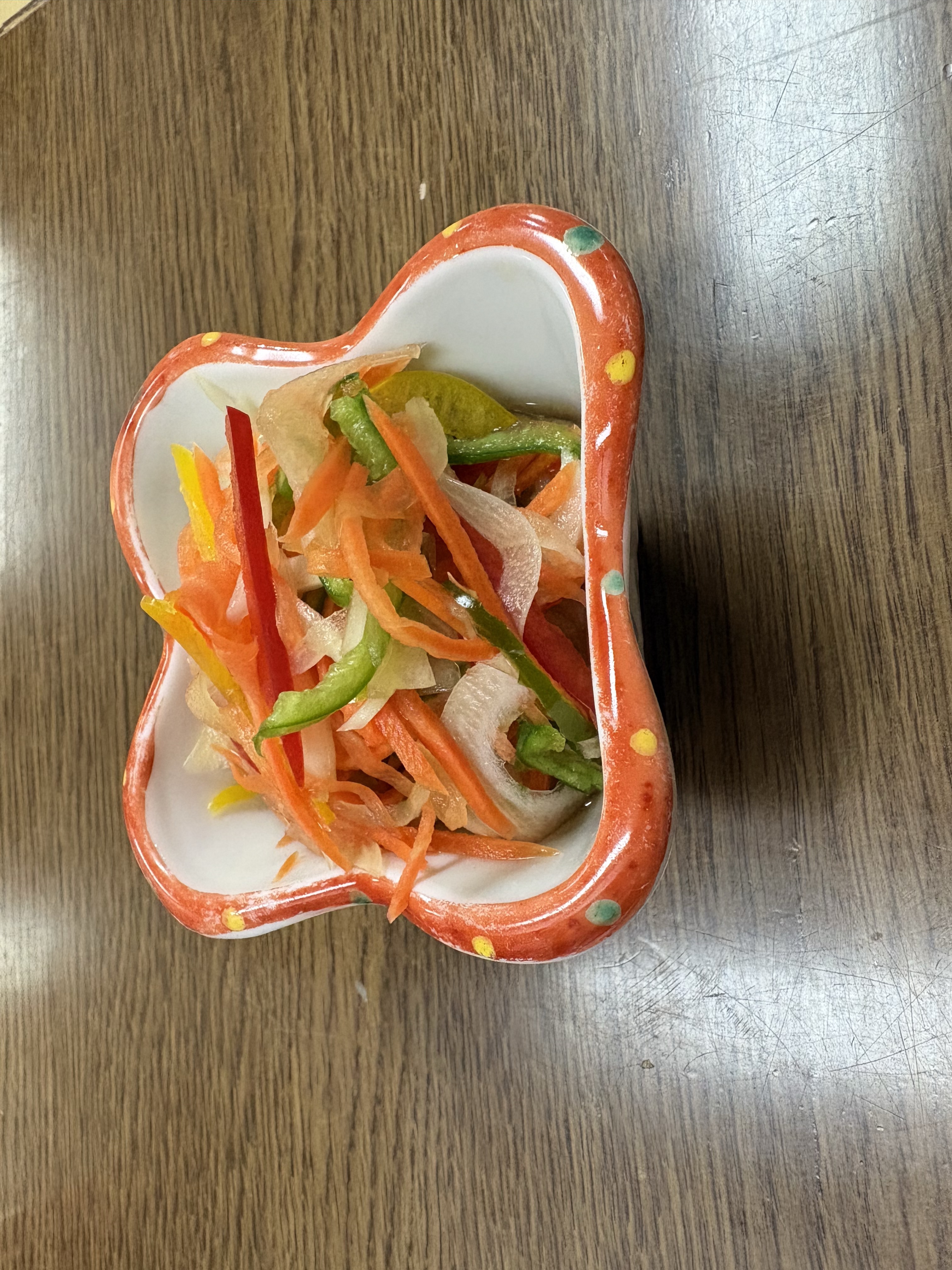 赤い華やかな器に、はもの南蛮漬けを盛り付けた、彩り鮮やかな一皿