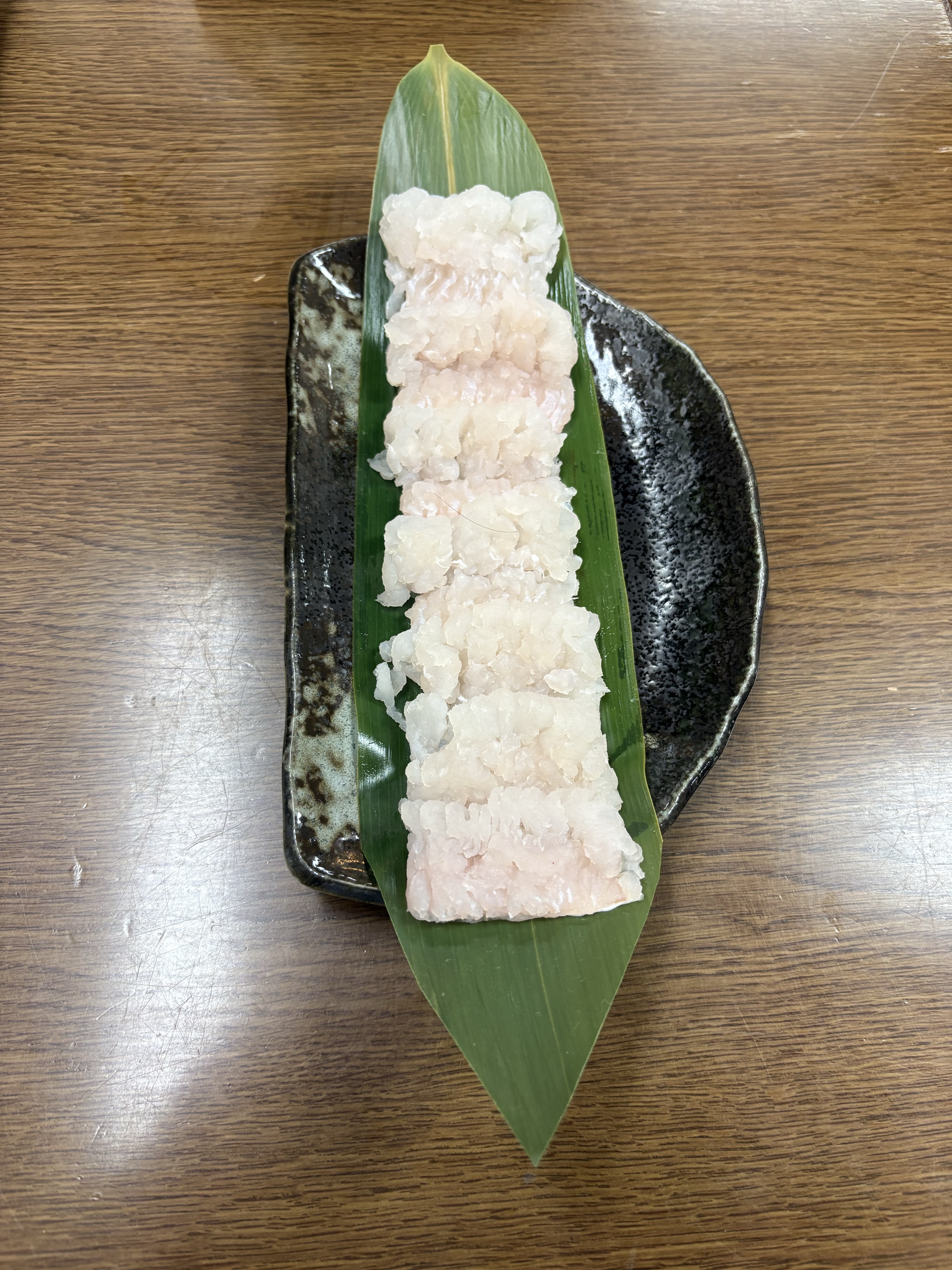 竹かごを背景に、はもの薄切り身が回転して積み重ねられた、まさに涮鍋用の一皿