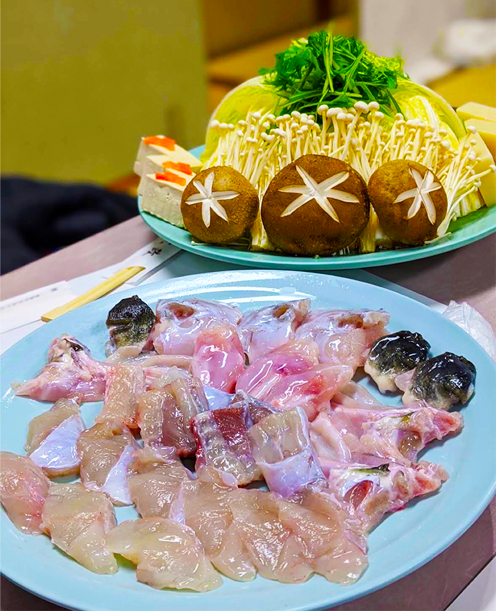 白菜・水菜・えのき・椎茸・豆腐を盛った鍋野菜と、手前にふぐの身とあらの皿